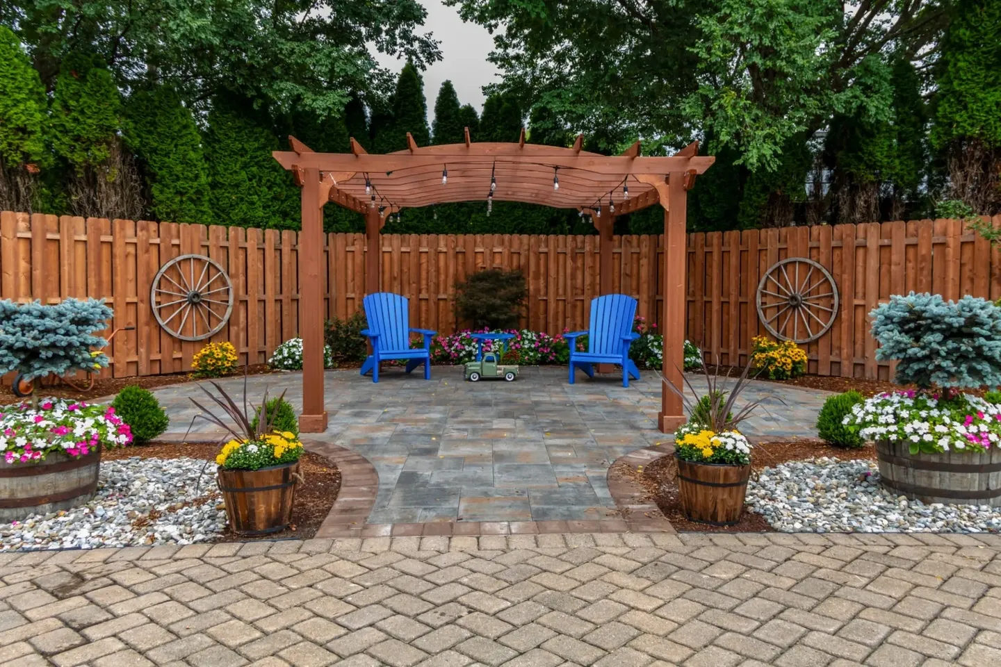Cozy backyard seating under a wooden pergola with blue chairs and decorative planters.