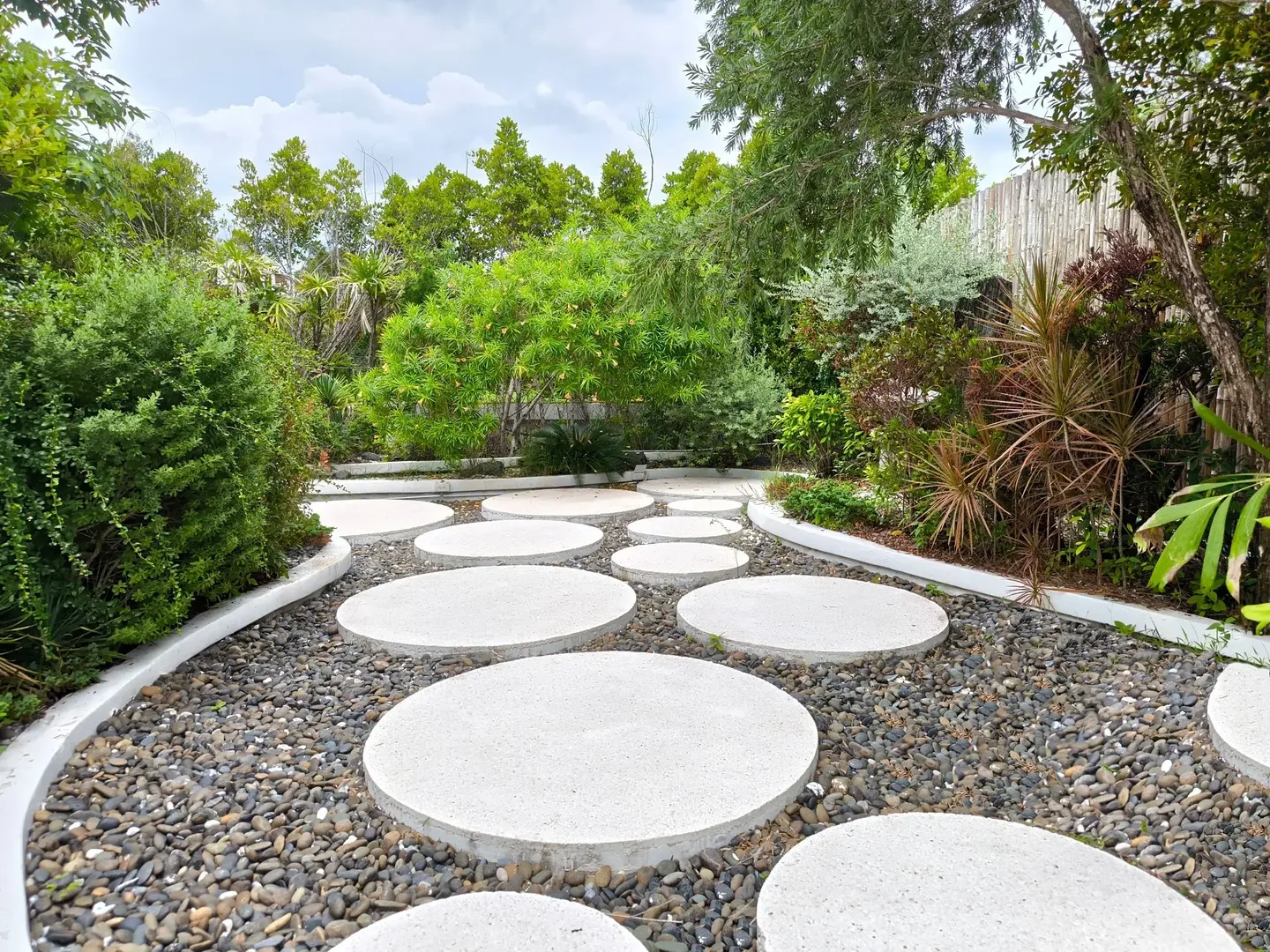 Round stepping stones create a path through a lush garden.