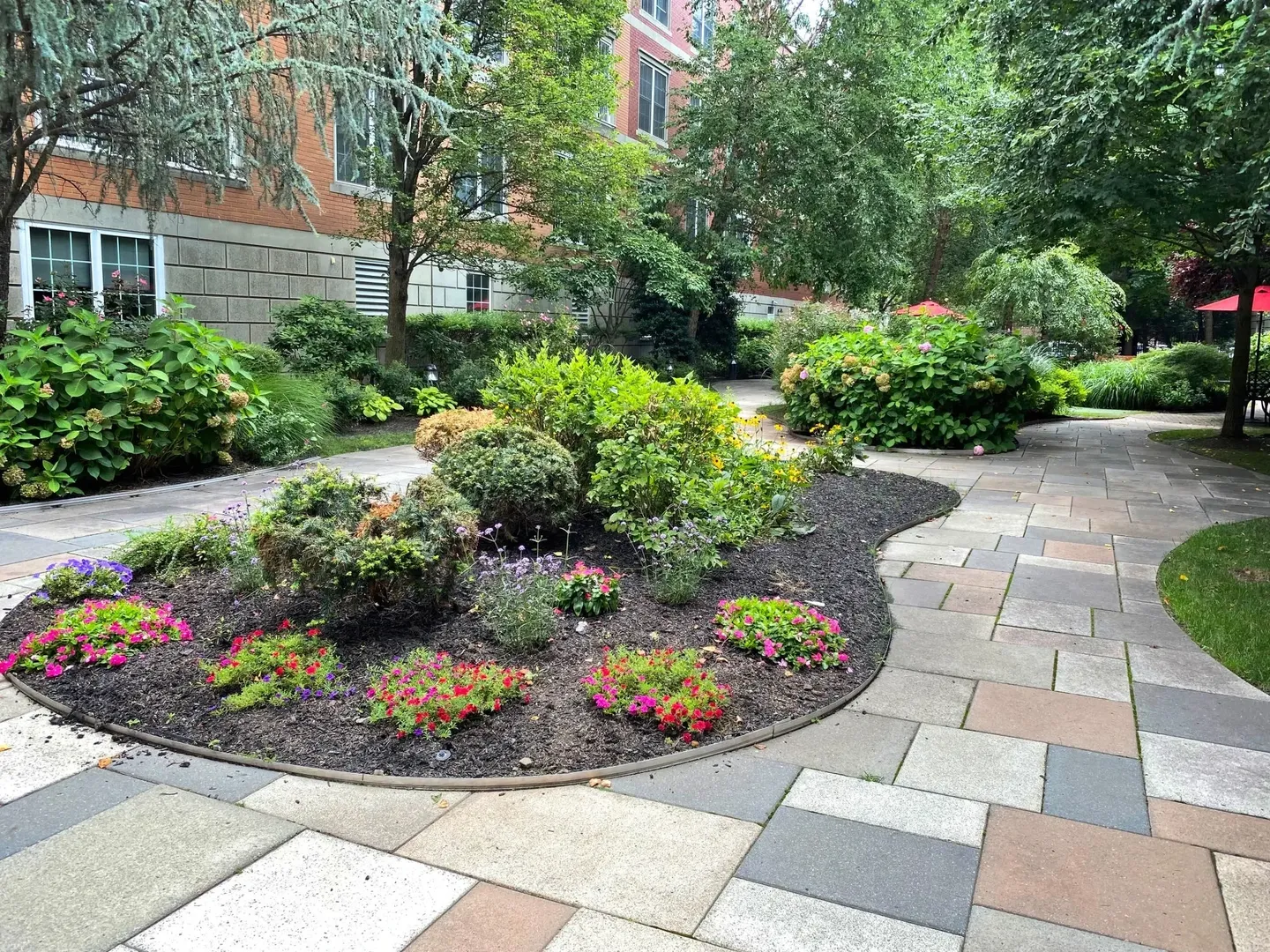 A landscaped garden with colorful plants and a curved stone pathway.